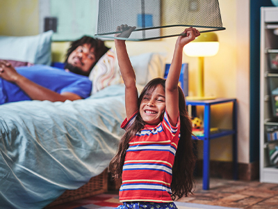 Smiling girl holds metal basket while her father rests in the bedroom.