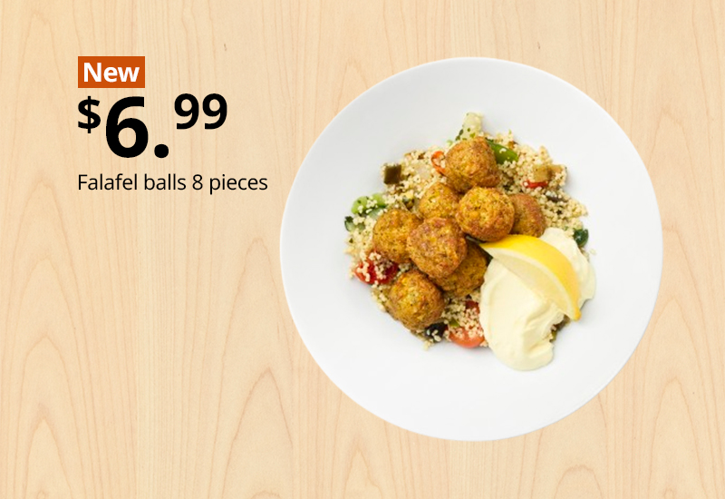 White plate with eight falafel balls served over couscous with sauce and a lemon wedge.