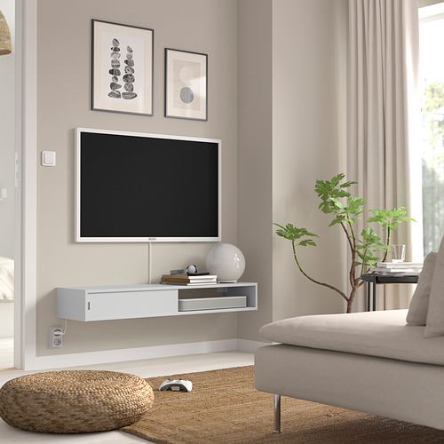 Sala de estar minimalista con estantería blanca SPIKSMED, tv, sofá y plantas.