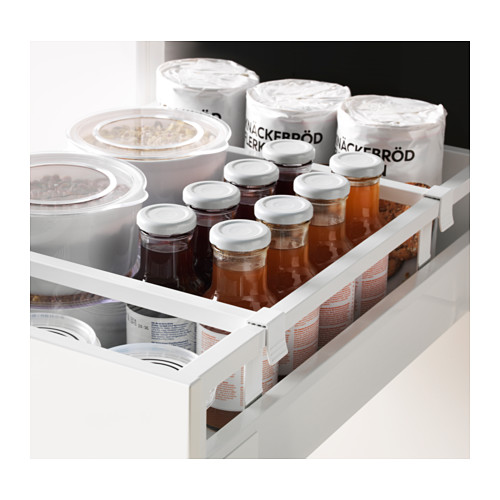 Cajón de cocina blanco con varios frascos y recipientes de vidrio transparentes y etiquetados.