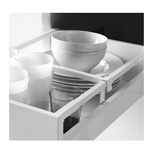 Cajón de cocina blanco y negro abierto, mostrando platos organizados: tazas, tazones y platos en cajón blanco brillante, con divisor para platos.