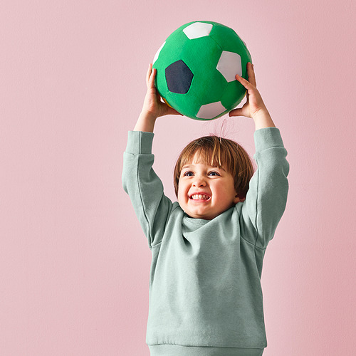 Un niño sostiene alegremente una pelota de fútbol sala verde y suave, ideal para jugar en familia.