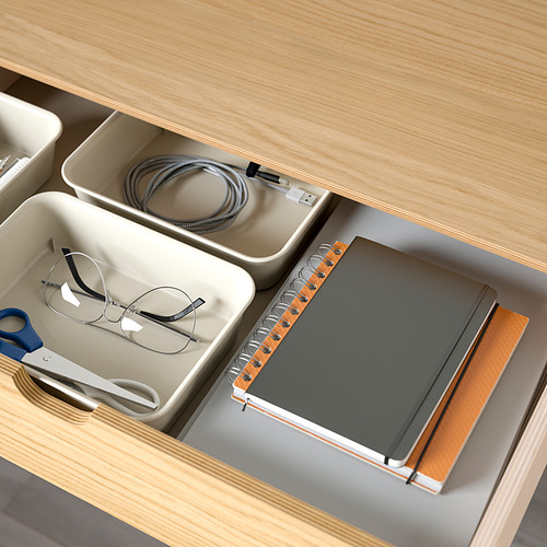 Cajón de escritorio organizado con gestión de cables y compartimentos de almacenamiento para papelería.