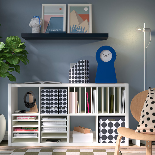 Sala de estar moderna con pared azul y estantes KALLAX que sostienen libros y decoración.