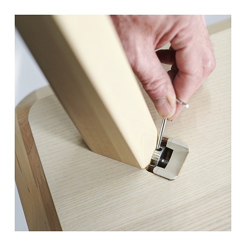 La persona monta muebles de madera clara usando una herramienta.