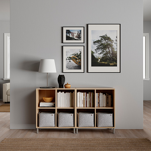 Sala de estar moderna con pared gris, grandes fotos de la naturaleza enmarcadas y estantería de madera.