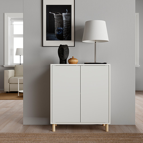 Salón moderno: mueble EKET blanco, lámpara, arte, suelo de madera.