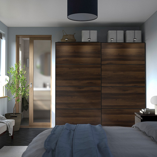 Dormitorio minimalista con gran armario de madera para pax sin palabras, cama azul y una planta en maceta.