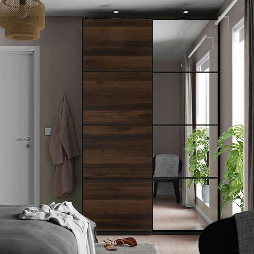 Dormitorio con grandes puertas correderas de armario: una con espejos y otra de madera, habitación reflectante con plantas.