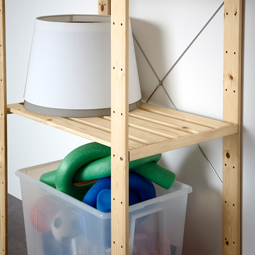 Estantería de madera con una lámpara en la parte superior y una papelera de almacenamiento que contiene fideos de piscina y otros artículos, lo que demuestra la funcionalidad de almacenamiento.