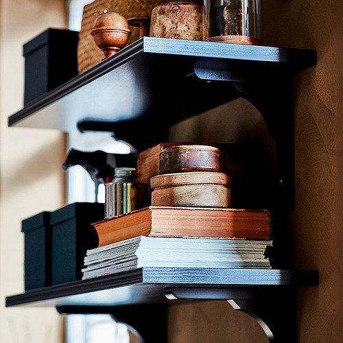 Estantería negra con libros apilados y cajas de madera. Bordes biselados y lisos. Almacenamiento con estilo.