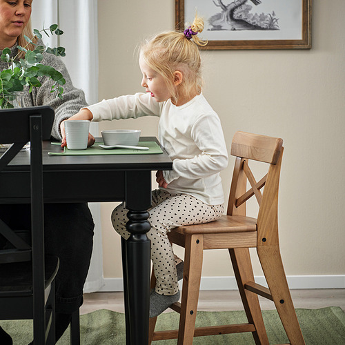 Descripción de la imagen: un niño pequeño se sienta en una silla junior, colocado de manera segura en una mesa de comedor, comiendo.