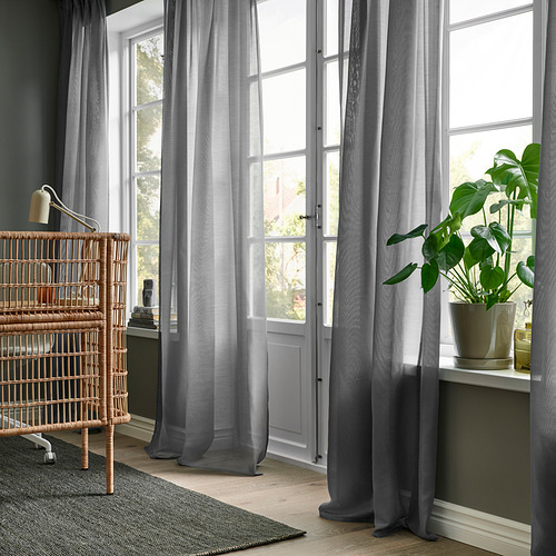 Habitación con cortinas STENFRÖ grises, estantería, alfombra, planta.