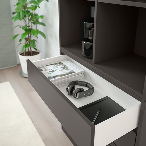 Cajón abierto de una unidad de almacenamiento moderna que exhibe auriculares y revistas.