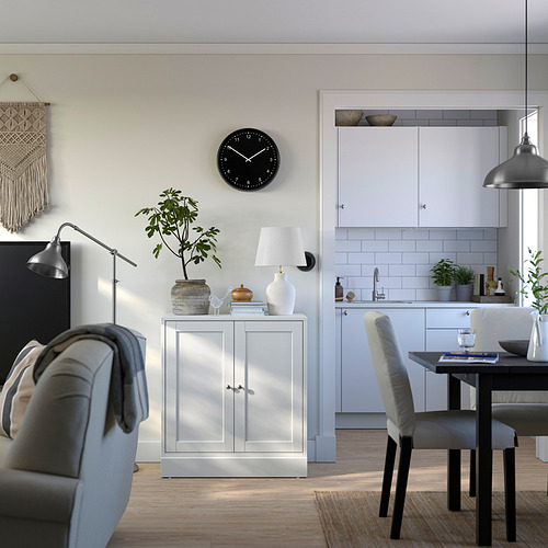 Moderna casa de concepto abierto con gabinete HAVSTA blanco, silla gris, planta, lámpara, reloj y comedor.