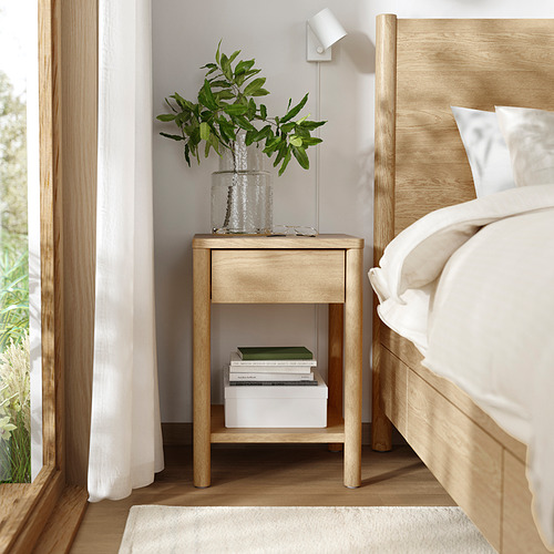 Dormitorio minimalista con muebles de madera, libros y jarrón.