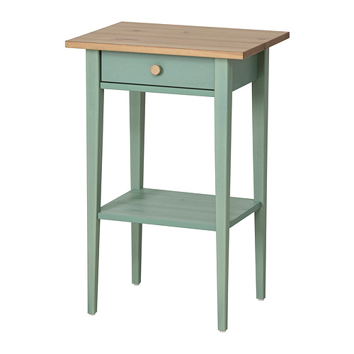 Una mesa auxiliar de madera HEMNES en color verde grisáceo con tapa de madera clara. Tiene un cajón y un estante, que ofrecen almacenamiento y exhibición.