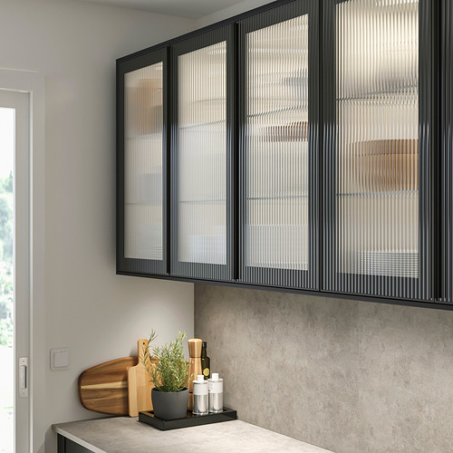 Cocina moderna con gabinete HEJSTA negro, puertas de vidrio de caña y hierba en maceta.