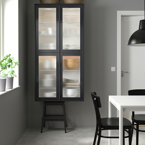 Cocina moderna con gabinete METOD negro con vidrio texturizado, de pie cerca de la ventana; Diseño elegante con sillas y un pequeño taburete.
