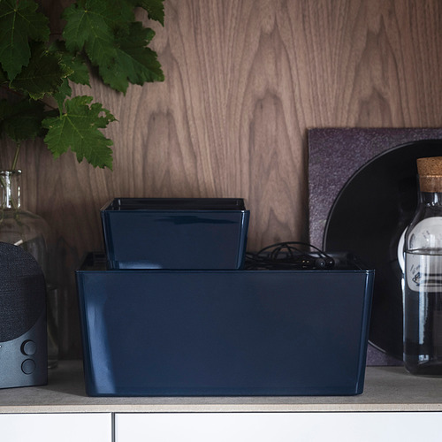 Dos cajas azules de KUGGIS sobre la mesa, con altavoz y botella.