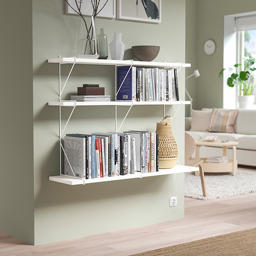 Estantería de pared blanca con artículos contra la pared verde salvia en la sala de estar beige.