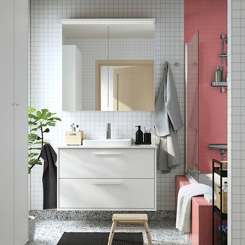 Baño moderno con lavamanos blancos, ducha roja, espejo, toallas, planta.