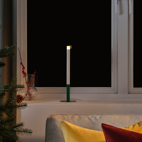 Vela verde, árbol de navidad, bayas rojas en el alféizar de la ventana.
