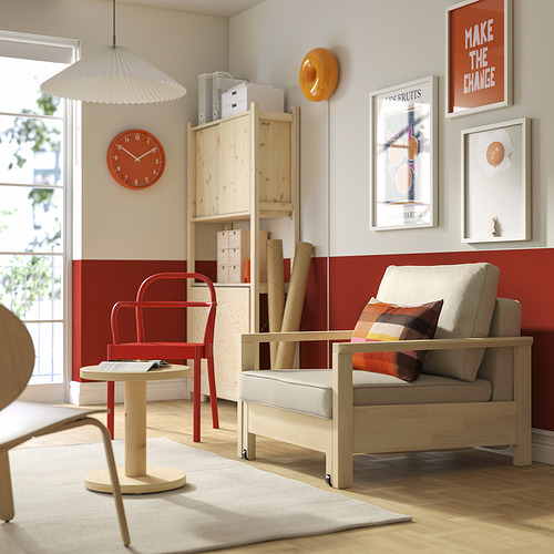 Acogedora sala de estar con sillón TORNSBORG, silla roja, pared de galería y gran ventanal.