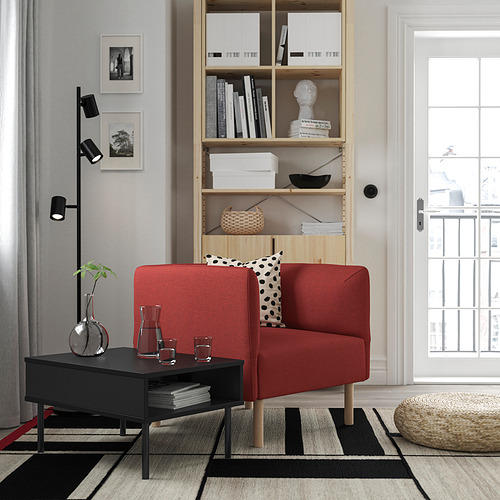 Sala de estar moderna con sofá lillem rojo, mesa de centro negra, alfombra en blanco y negro, estantería de madera y lámpara de pie negra.