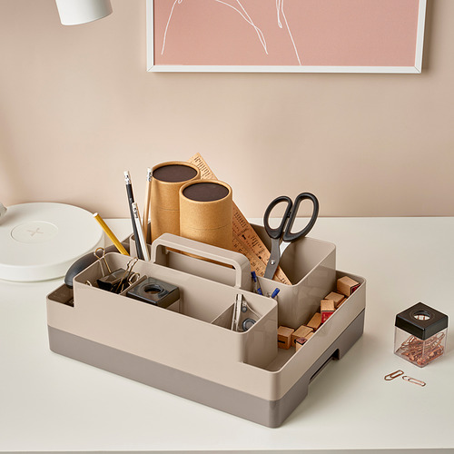 Organizador de escritorio con tijeras, bolígrafos, calculadora y papel. Múltiples compartimentos y un asa para transportar.
