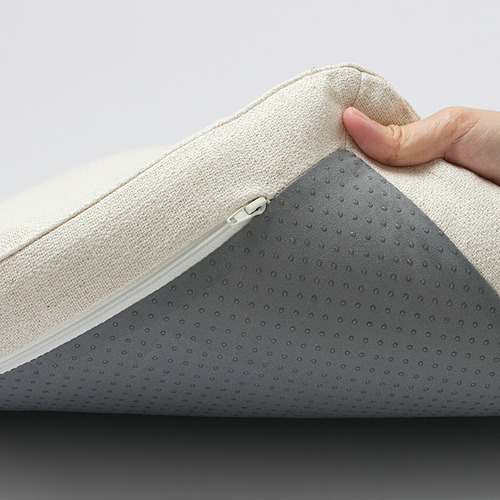 Una mano levantando una funda de asiento acolchada, mostrando su cierre de cremallera.