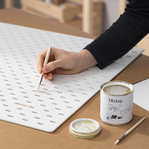 Persona usando pincel para pintar un tablero perforado blanco con pintura TRIXIG.