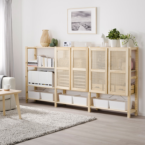 Unidad de almacenamiento IVAR con puertas de madera y bambú, amplios estantes y varios artículos. Alto, al lado de una gran planta y debajo de la obra de arte.