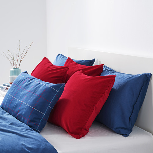 Cama con almohadas rojas y azules; Terciopelo rojo en el centro, estampado azul y liso en los laterales.