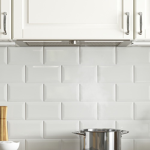 Cocina moderna con gabinetes blancos, manijas plateadas y estufa de acero inoxidable. Campana extractora oculta con iluminación led y filtro de grasa.