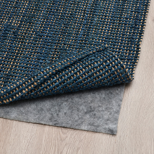 Alfombra de yute azul oscuro con alfombrilla antideslizante en la parte inferior, ideal para salones o comedores, aportando comodidad y estabilidad.