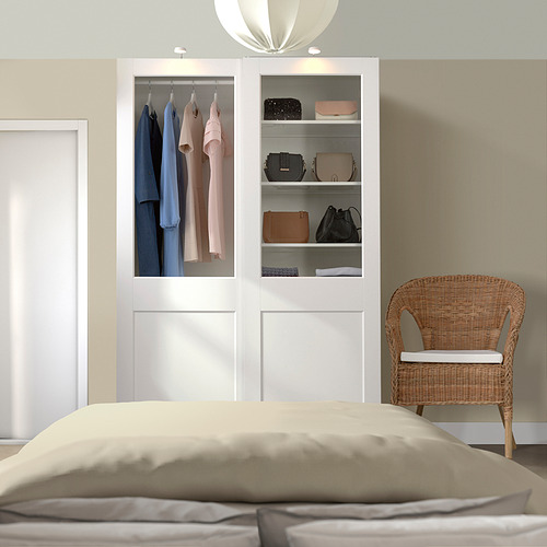 Dormitorio moderno con armario PAX blanco, luces y silla de mimbre.