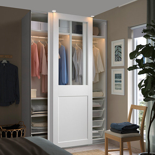 Moderno armario blanco PAX con puertas de cristal, que muestra ropa y accesorios organizados.