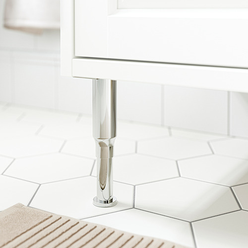 Una elegante pata de acero inoxidable sostiene un armario blanco sobre un suelo de baldosas, que muestra muebles de baño modernos.