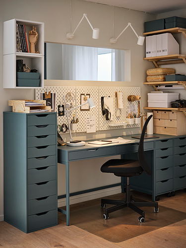 Moderna oficina en casa con configuración de tablero perforado azul y verde SKÅDIS, silla negra y escritorio gris con estantes de almacenamiento organizados y una pizarra blanca.