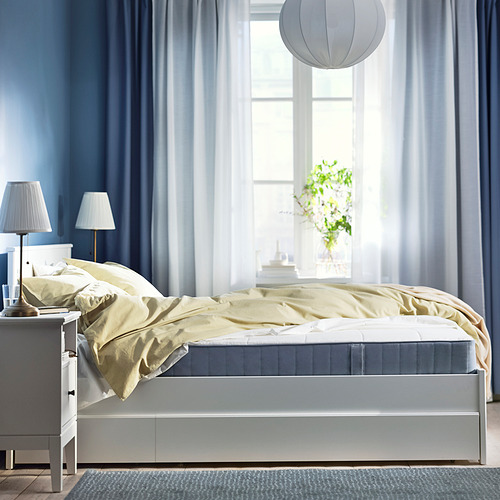 Dormitorio tranquilo con cortinas azules, cama blanca y mantas amarillas; Un espacio acogedor, sencillo y acogedor.