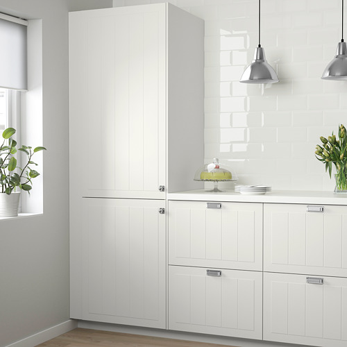 Armarios de cocina blancos de estilo rústico con paneles ranurados, acabado lacado. Armarios altos superiores, ventana con plantas.