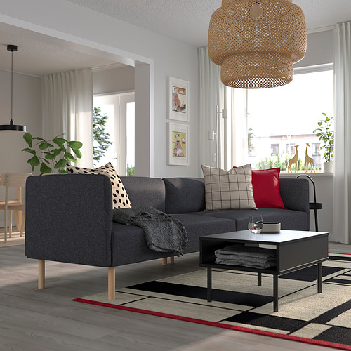 Sala de estar moderna con sofá modular gris, cojines, mesa de centro, lámpara colgante, plantas y cuadros enmarcados.