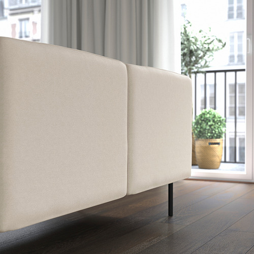 Moderno sofá modular de color crema con suelo de madera, gran ventanal y planta.