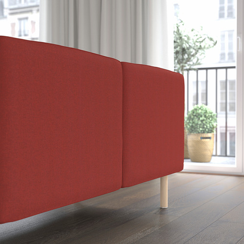 Sección de sofá modular rojo cerca de una ventana grande y planta en una oficina o en casa.