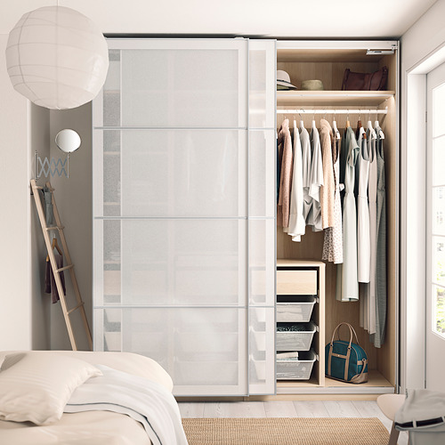 Dormitorio moderno con un armario blanco PAX con ropa, estanterías y un bolso azul en el suelo.