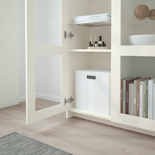 Librería BRIMNES blanca con puertas de cristal expositores de libros y decoración, anclada de forma segura a la pared.