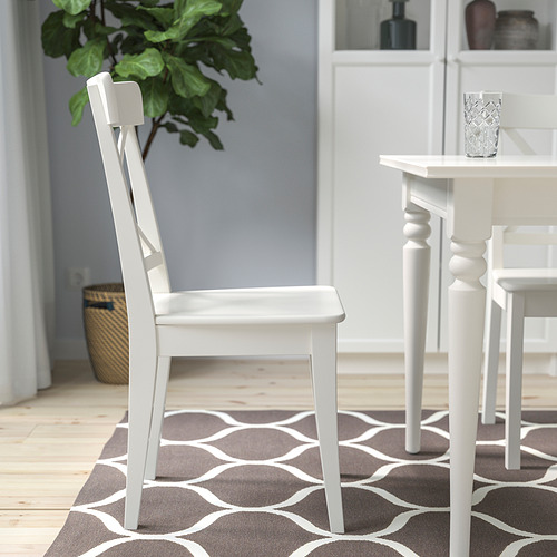 Silla blanca de la serie INGOLF cerca de la mesa de comedor sobre alfombra estampada