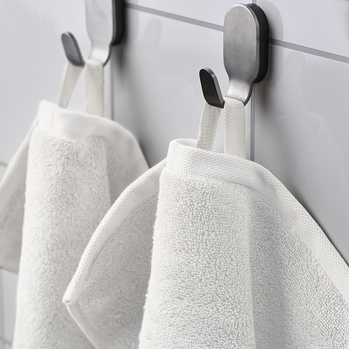 Dos toallas blancas cuelgan de modernos ganchos negros en un baño.