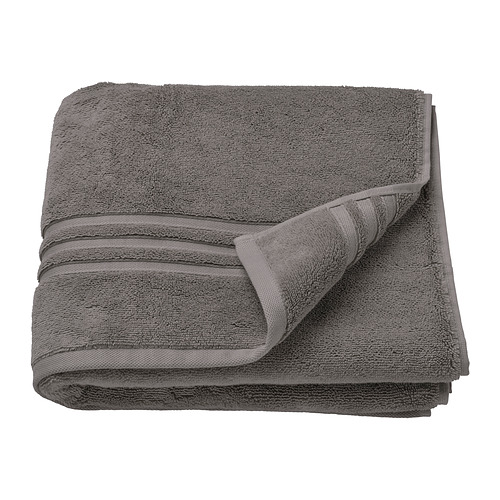 Una toalla BROKGLIM gris oscuro cuidadosamente doblada, hecha de algodón 100% orgánico, con un borde tejido y forma cuadrada.